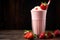 profile shot of a glass of strawberry milkshake with a straw