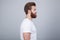 Profile shot of handsome male with trendy hairdo and beard, looks aside with serious expression, has thick red beard,