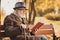 Profile side photo of attentive concentrated old man rest relax autumn town trees park read encyclopedia book sit bench