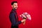 Profile side photo of young cheerful gentleman give bouquet in copyspace birthday isolated on red color background