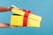 Profile side view closeup of human hand in white surgical gloves holding and opening yellow gift box