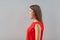 Profile side view portrait of crazy wild aggressive brunette young woman in red shirt standing, looking forward and screaming or