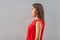 Profile side view portrait of shocked beautiful brunette young woman in red shirt standing, looking forward with surprised