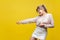 Profile side view of positive assertive young woman with fair hair in casual beige blouse, isolated on yellow background