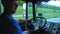 Profile of smiling lorry driver riding through countryside at sunset background. Happy man controlling his truck and