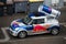 Profile view of mini cooper with a red bull branding decoration and a red bull can on the roof parked in the street