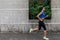 Profile view of a sporty young woman working out outdoors. Fitness girl running on sidewalk.