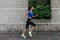 Profile view of a sporty young woman working out outdoors. Fitness girl running on sidewalk.
