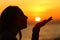 Profile of a woman blowing or kissing sun at sunset