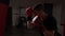 Profile of young athletic boxer wearing red boxing gloves and hitting the punching bag nervously in slow motion -