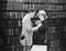 Profile of a young man attaching a brooch on a young woman\'s overcoat in a library