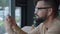 Profile of a young man with a beard. He sits in a cafe with phone