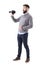 Profile of young shocked casual man holding and looking at virtual reality glasses.