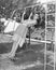 Profile of a young woman swinging on a swing in a garden