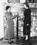 Profile of a young woman in an uniform measuring weight of another young woman on a weighing scale