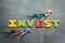 Profit or growth from investment concept, arrows pointing up as chart with colorful letters building the word INVEST on loft