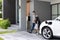 Progressive dad and daughter charging EV car from home charging station.