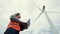 Progressive engineer working with the wind turbine, with the sky as background.