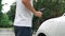 Progressive man install cable plug to his EV car from home charging station.