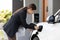 Progressive woman recharge her EV car at home charging station.