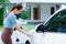 Progressive woman recharge her EV car at home charging station.