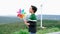 Progressive young asian boy playing with wind turbine toy at wind turbine farm.