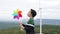 Progressive young asian boy playing with wind turbine toy at wind turbine farm.
