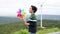 Progressive young asian boy playing with wind turbine toy at wind turbine farm.