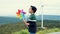 Progressive young asian boy playing with wind turbine toy at wind turbine farm.