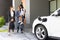 Progressive young parents and daughter living in a home with an electric car.