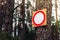 Prohibiting red road sign hanging on the tree in forest. Security in the forest concept