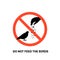 Prohibition sign with text do not feed the birds and hand silhouette giving food to pigeon