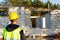 Project architect stands near construction site of a house with the walls are made of a porous concrete block and a brick.