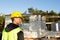 Project architect stands near construction site of a house with the walls are made of a porous concrete block and a brick.