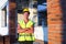 Project architect stands near construction site of a house with the walls are made of a porous concrete block and a brick.