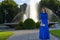 Prom girl in fashionable dress posing in the park with the fountain in the background