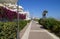 promenade with bright pink flowers and white parasols in mediterranean town Caorle in Adriatic Sea (North Italy)