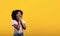 Promo concept. Amazed black woman looking at empty space, touching her face in surprised gesture, yellow background