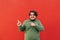 Promotional photo of a young cheerful hispanic obese man pointing his fingers at a red background, feeling excited and positive