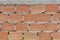 The pronounced texture of corpulent brick on the wall with a cement seam with cement hat