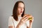 Proper nutrition, healthy fast food, unhealthy choice. Young amazed astonished woman wearing white t-shirt holding in hand burger