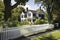 a property with a classic exterior, featuring a white picket fence and black shutters