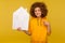 Property purchase. Happy bright woman with fluffy curly hair in urban style hoody pointing at paper house