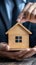 Property safeguarded Businessman protects wooden home model with his hand