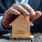 Property safeguarded Businessman protects wooden home model with his hand