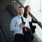 Pros in business travel. a businessman and businesswoman traveling down an escalator in an airport.