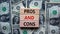 Pros and cons symbol. Wooden blocks with words `Pros and cons`. Beautiful background from dollar bills. Business, pros and cons
