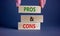 Pros and cons symbol. Wooden blocks with words `Pros and cons`. Beautiful grey background, businessman hand. Business, pros and