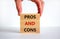 Pros and cons symbol. Wooden blocks with words `Pros and cons`. Beautiful white background, businessman hand. Business, pros and