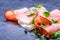 Prosciutto. Curled Slices of Delicious Prosciutto with parsley leaves on granite board. Prosciuto with spice cherry tomatoes